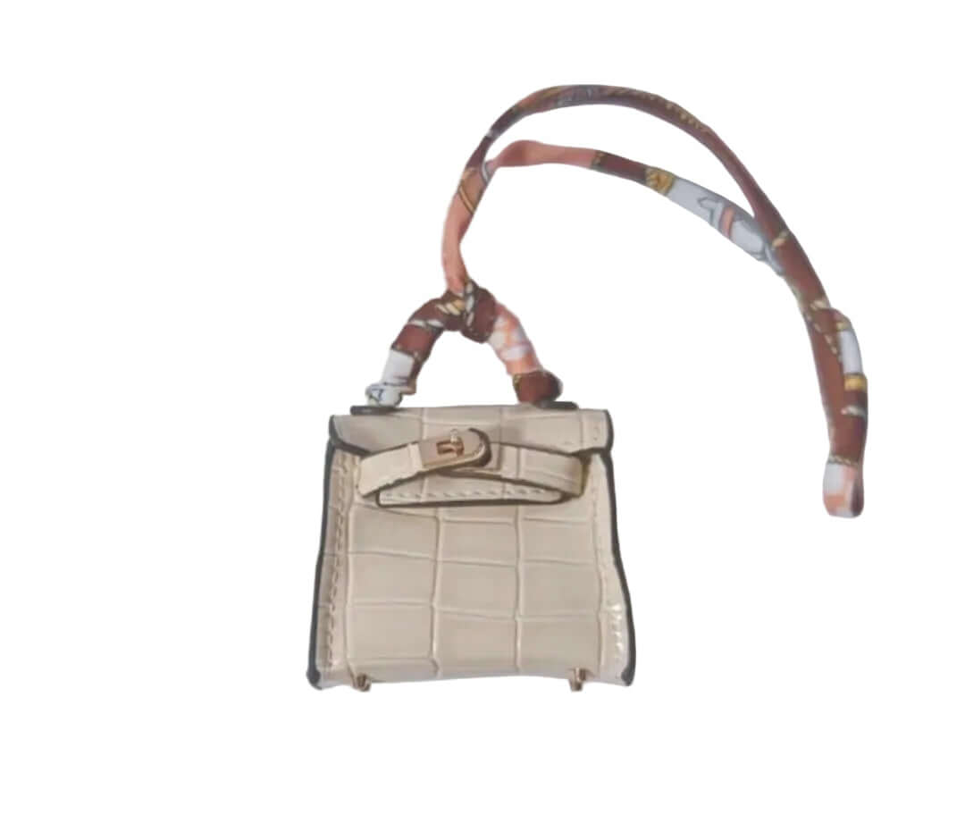 Small beige handbag with a patterned strap on a light gray background