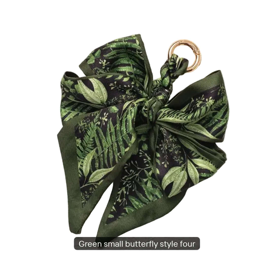 Green leaf-patterned bow keychain on a textured white background
