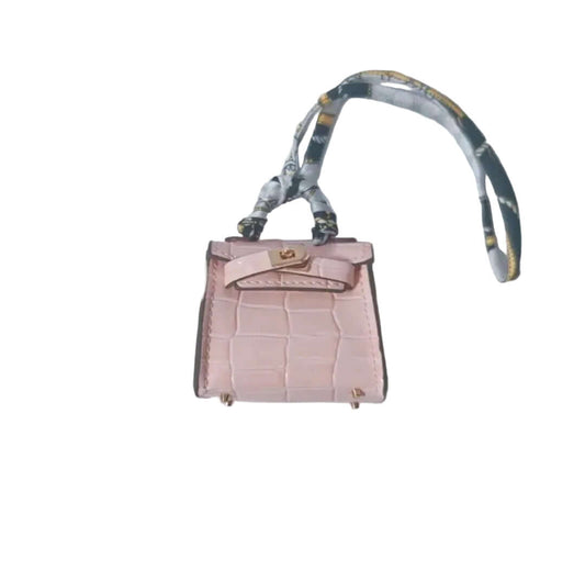 Pink handbag with a floral strap on a light gray background