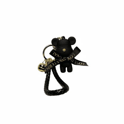 Black teddy bear keychain with a gold tag on a white background
