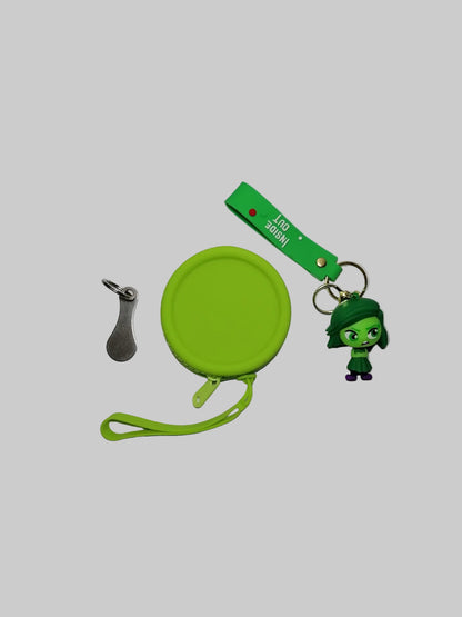 Green keychain with a small character, spoon-shaped keychain, and round green case on a white background