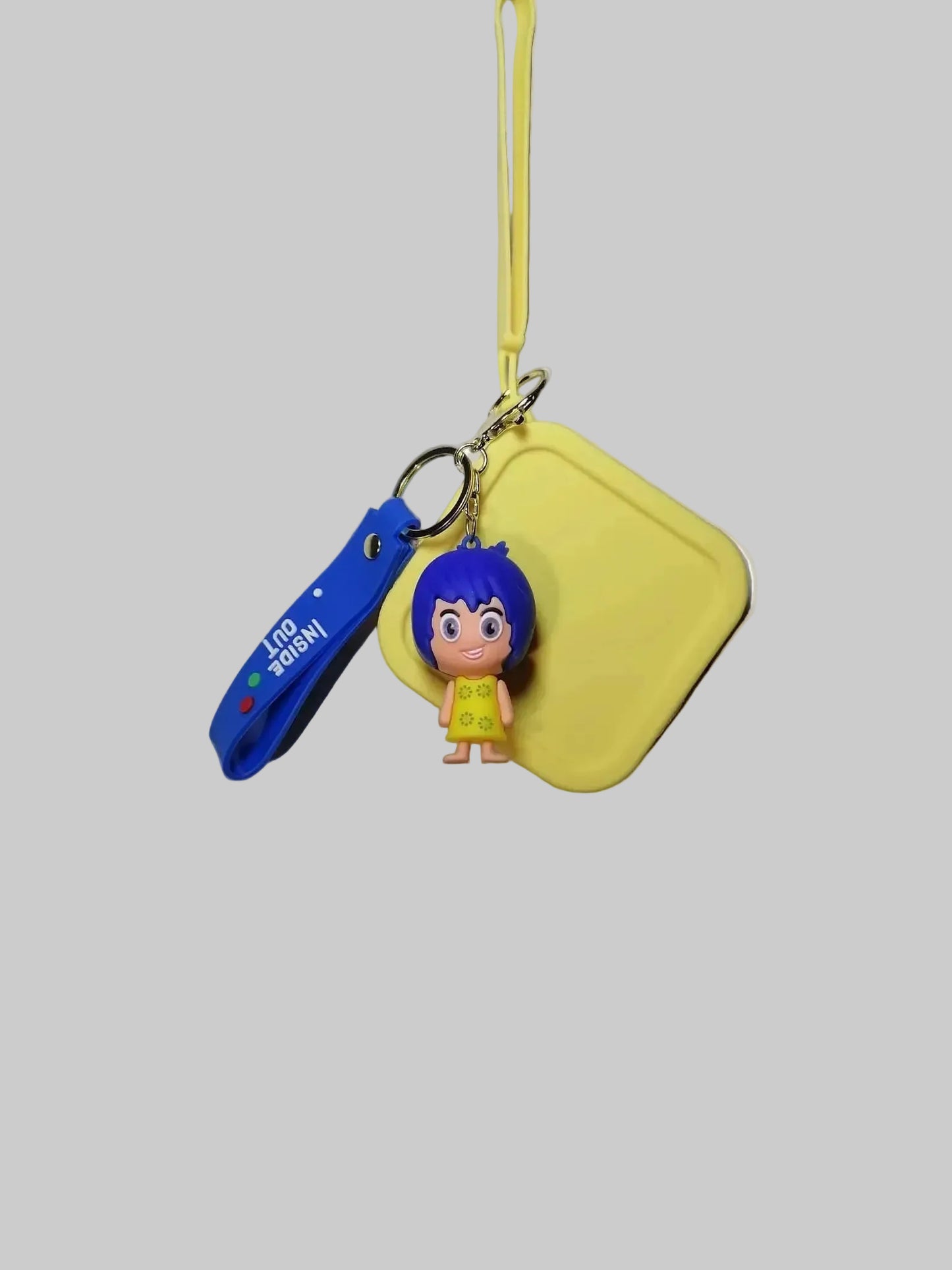 Keychain with cartoon character, blue tool, and yellow pouch on a gray background