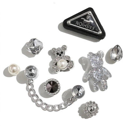 Collection of decorative pins with gemstones and a branded box on a white background