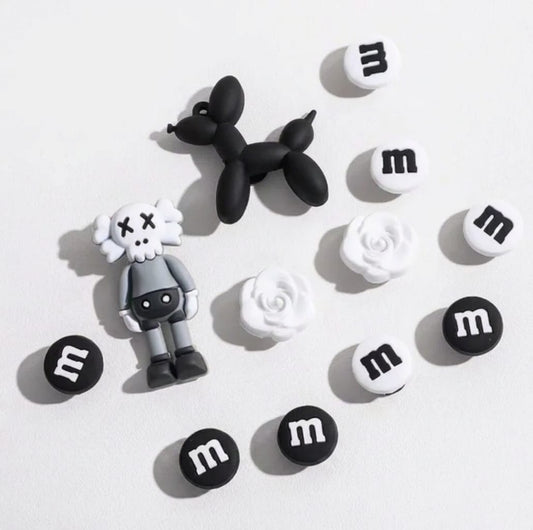 Black and white figurines on M&M candy buttons against a light gray background