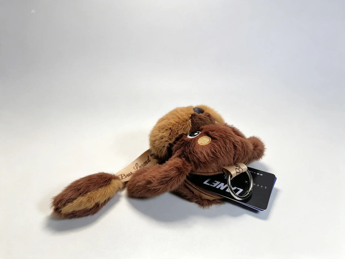 A plush dog keychain in shades of brown and tan, featuring a black metal keyring.