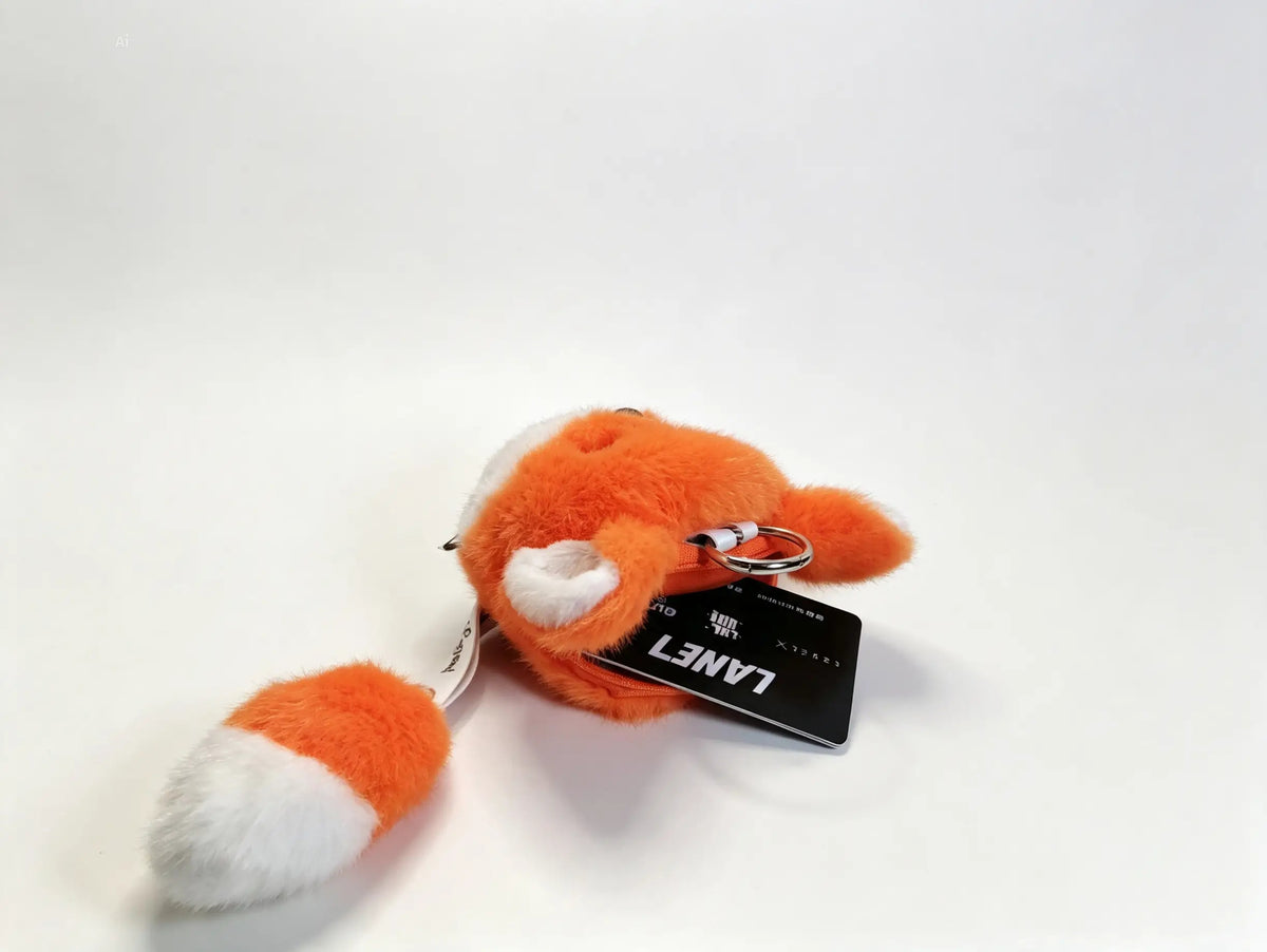 An orange and white plush fox keychain with a photographed on a clean white background.
