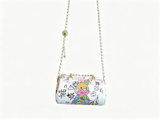 A white shoulder bag with a gold chain strap, decorated with colorful graffiti-style cartoon artwork and black doodle text, shown against a plain white background.