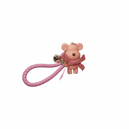 Pink teddy bear keychain with a gold bell on a white background