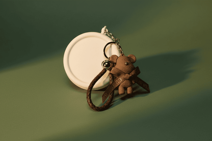 Brown teddy bear keychain on a green background