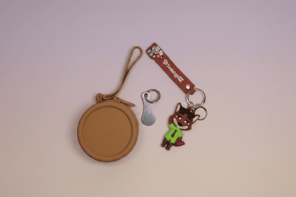 Round brown case, keychain with cartoon character, and metal key on a light pink background