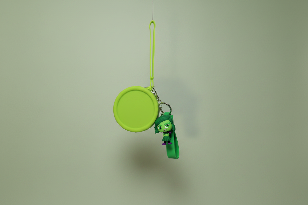 Green character charm on a string against a plain background