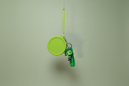 Green character charm on a string against a plain background