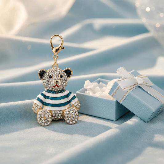A rhinestone teddy bear charm in a striped or plaid enamel outfit