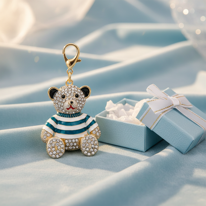 A rhinestone teddy bear charm in a striped or plaid enamel outfit