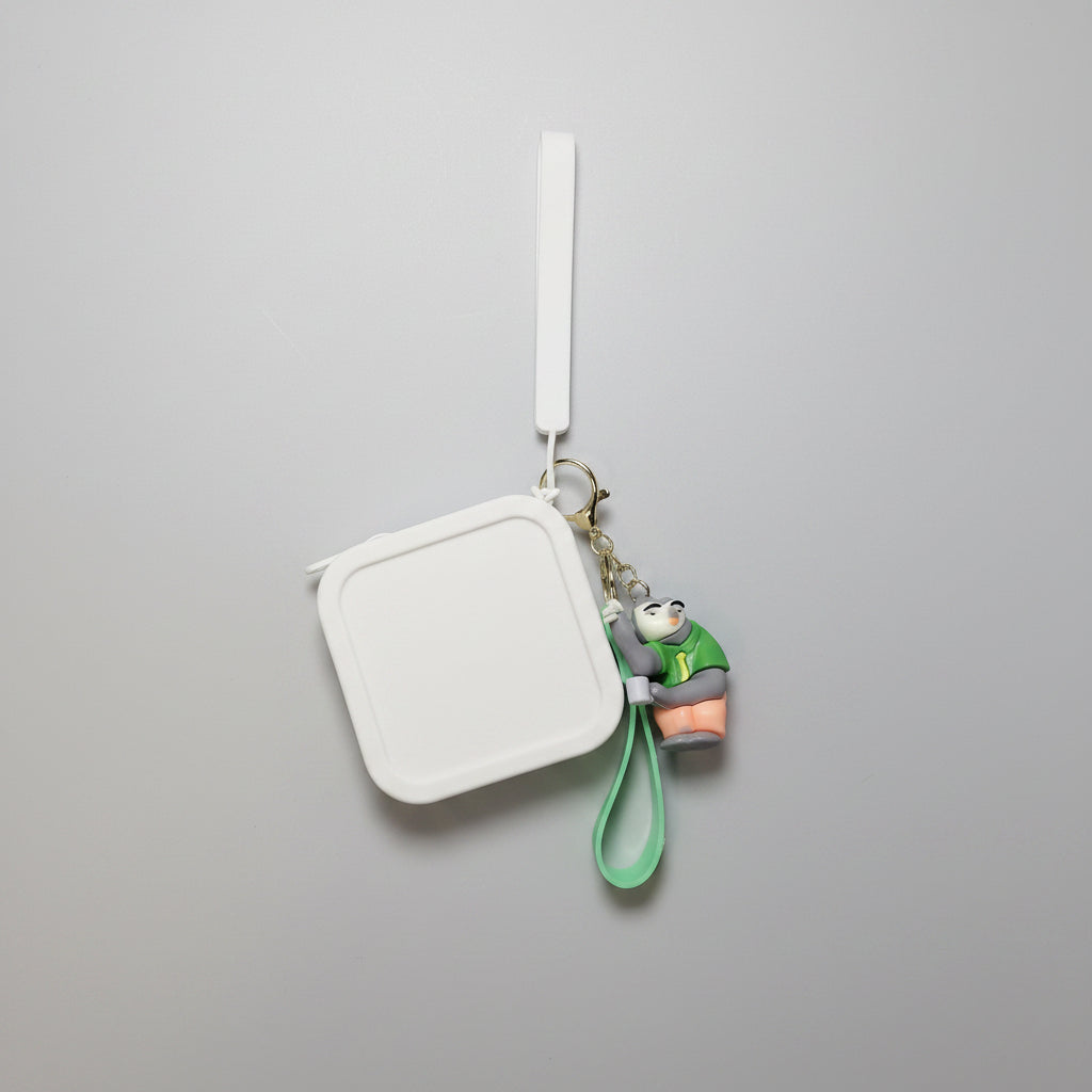 Keychain with a small character attached to a rectangular mirror on a textured white surface