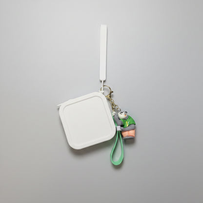 Keychain with a small character attached to a rectangular mirror on a textured white surface